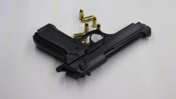 Black handgun with ammunition on a white surface.