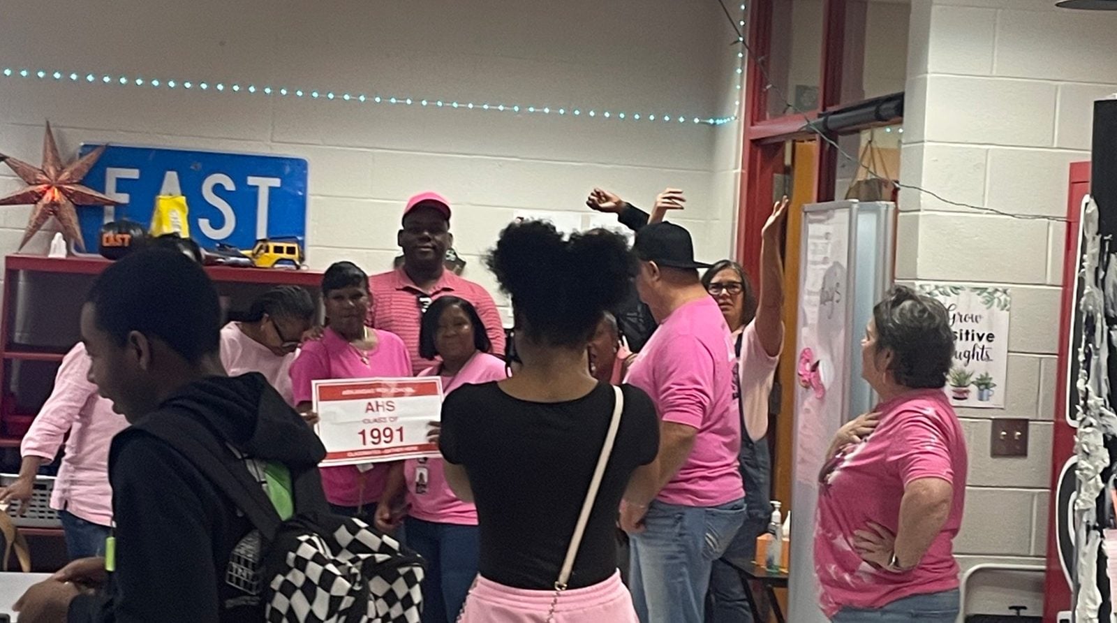 Class of 1991 members in pink shirts hold a 1991 sign inside the Arkansas High EAST room. Submitted photo. Class of 1991 members in pink shirts hold a 1991 sign inside the Arkansas High EAST room