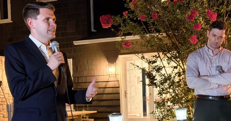 James Talarico in a navy blazer speaking into a handheld microphone at an outdoor evening campaign event, with Jon Ossoff standing behind him with arms crossed