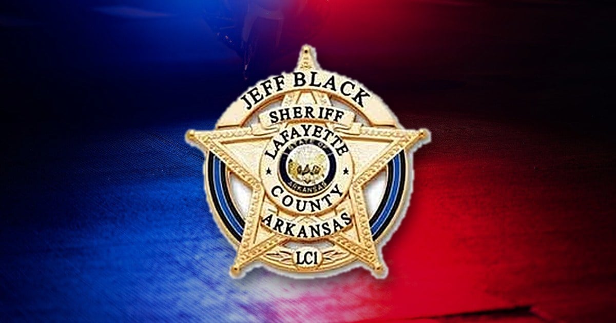 Lafayette County, Arkansas, sheriff's badge over red and blue police lights reflected on pavement.