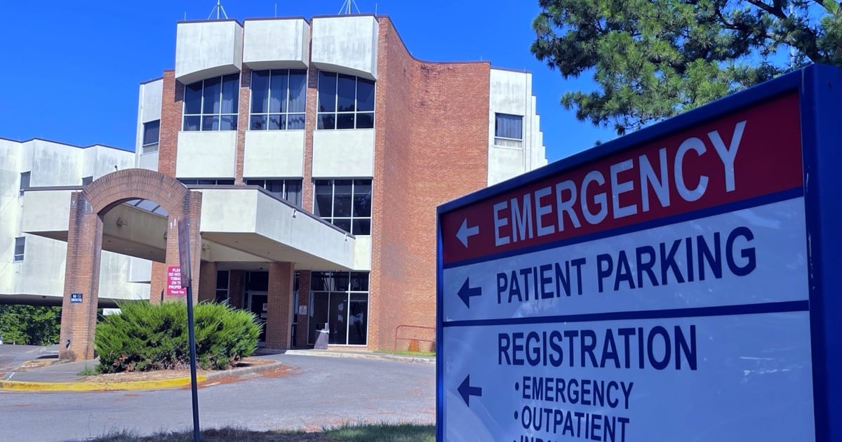 Brick and white McCurtain Memorial Hospital building behind an emergency and patient parking sign.