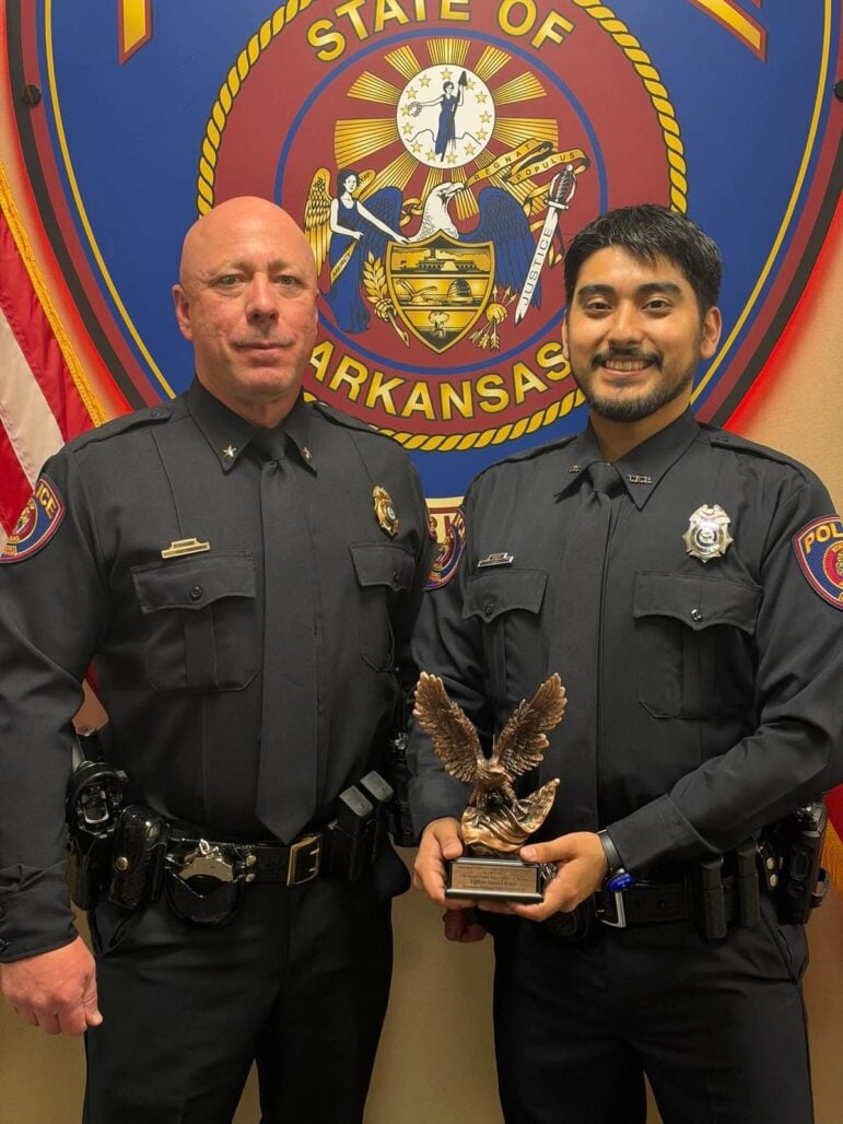 Texarkana, Arkansas, police Officer Daniel Rojas holds a bronze eagle trophy in front of the department seal.