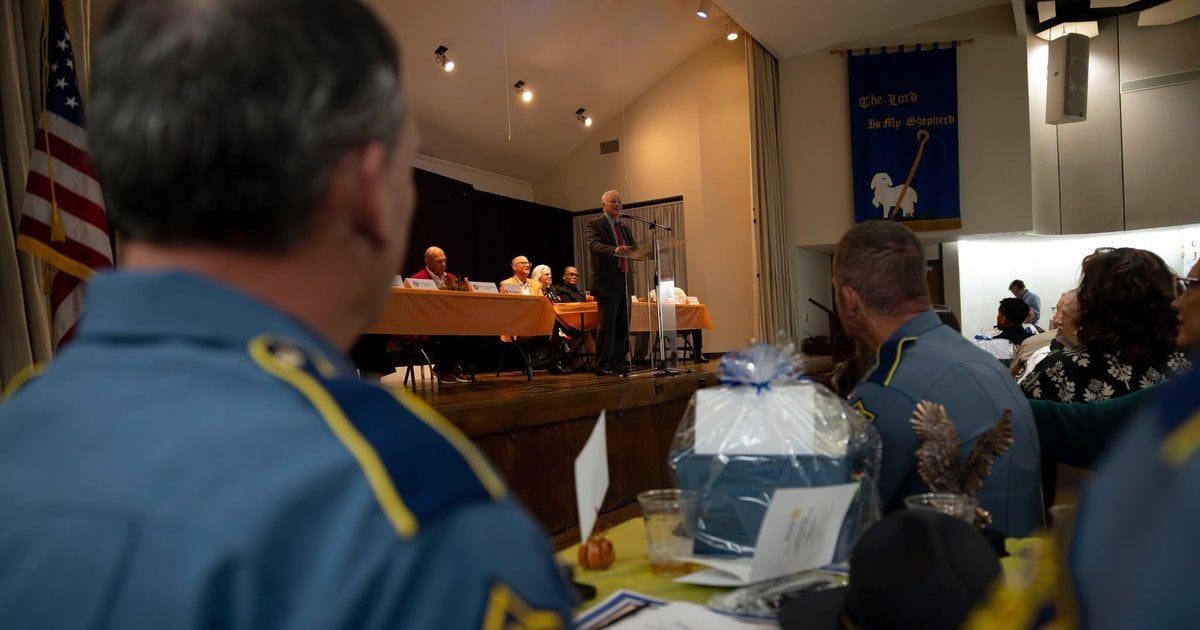 Arkansas Attorney General Tim Griffin speaks from a podium as uniformed officers watch from banquet tables.