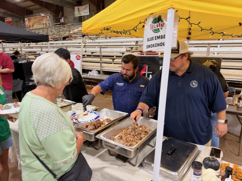 Blue Ember Smokehouse staff serving smoked pork to a guest