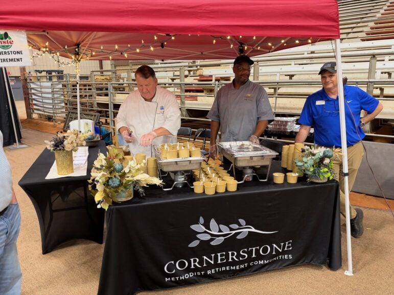 Three Cornerstone staff members behind a black-draped table of samples