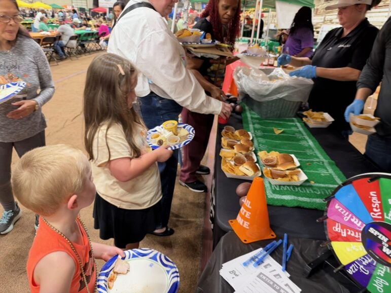 Two children taking sliders from a table decorated like a football field