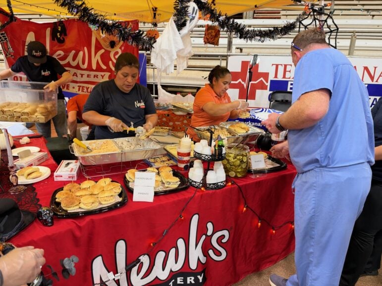 Newk's Eatery booth with trays of sandwiches on a red tablecloth